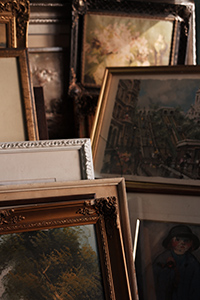 A selection of paintings in a variety of frames.